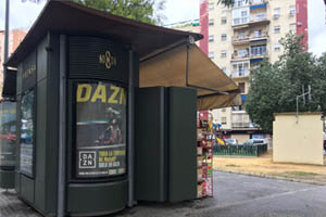 Un Kiosco con publicidad y personas junto al puente de Triana en Sevilla
